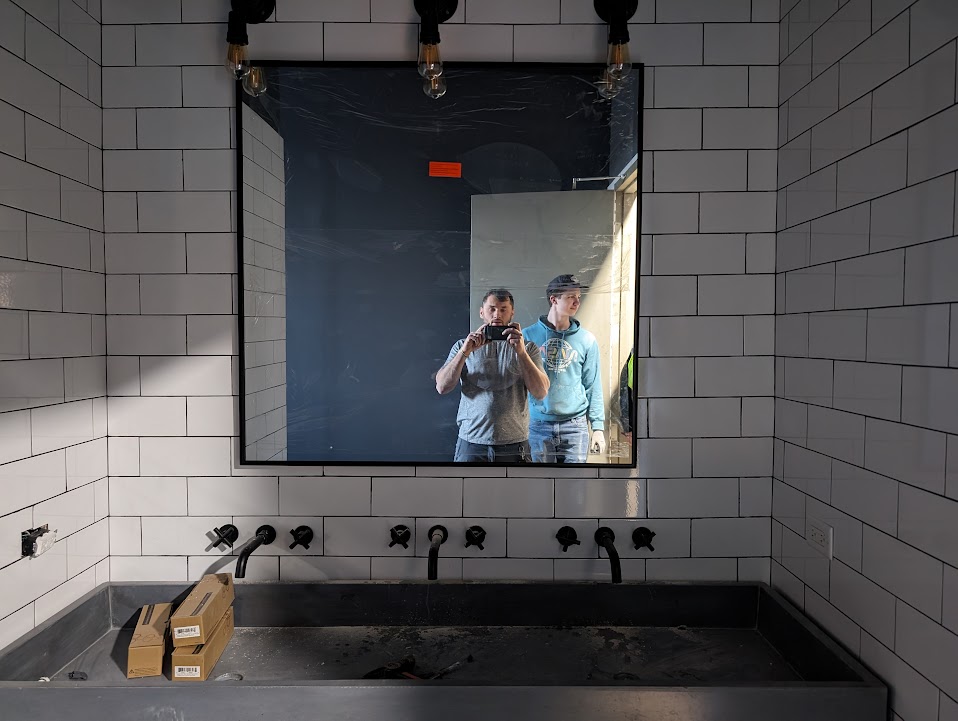 Black-framed trough sink with wall-mount faucets and subway tile surround