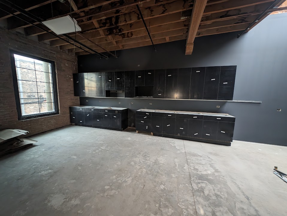 Dark custom cabinet installation in commercial build-out with brick and large window