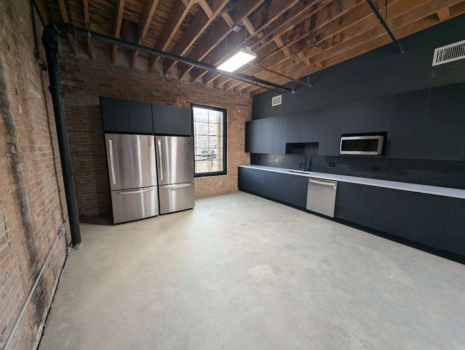 Finished commercial kitchen with matte black cabinets and exposed brick wall