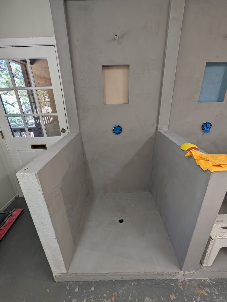 Custom microcement shower surround with seamless walls, floor, and built-in niche