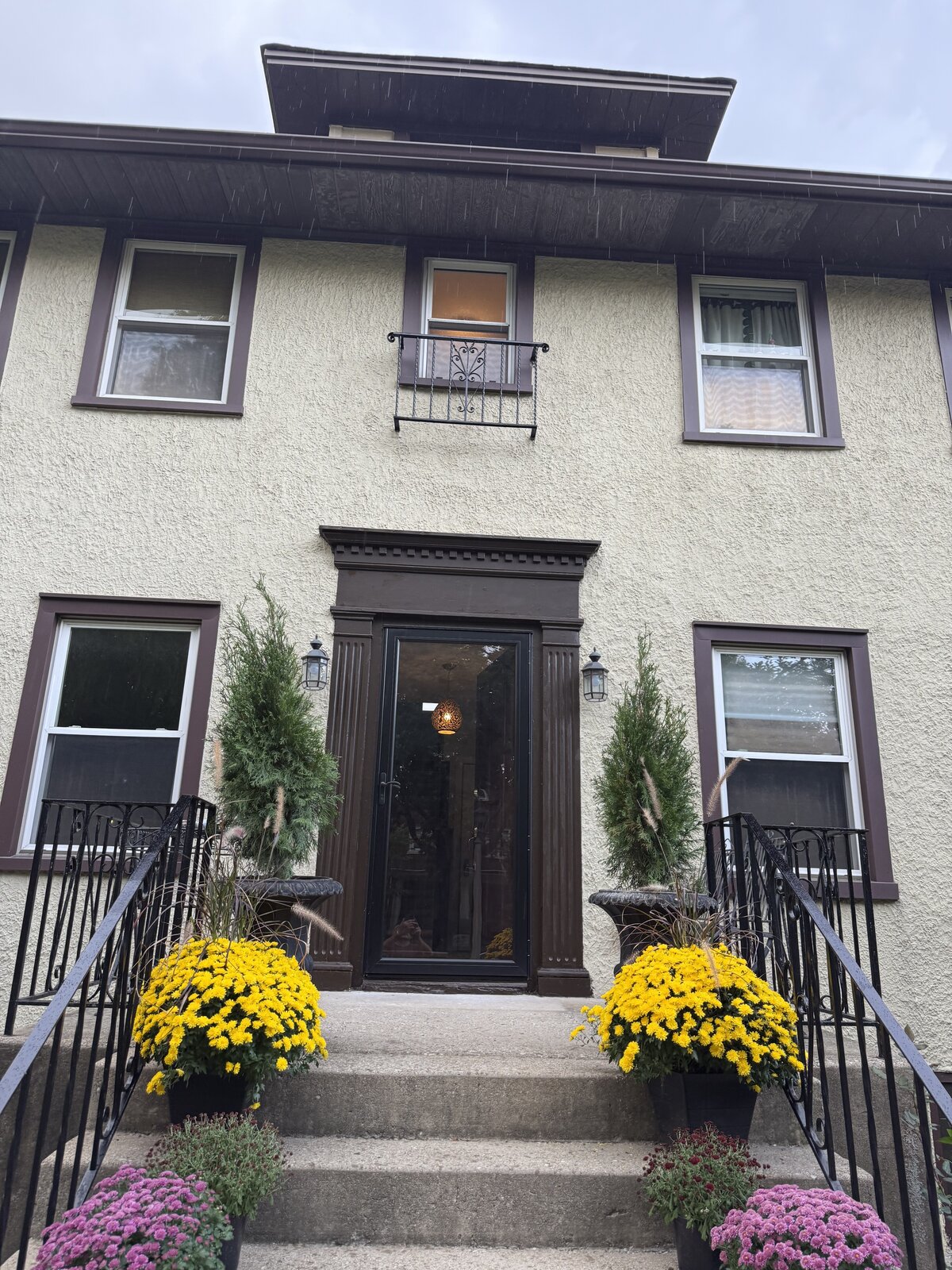 Restored front entrance with refinished dark wood door surround and seasonal planters, after