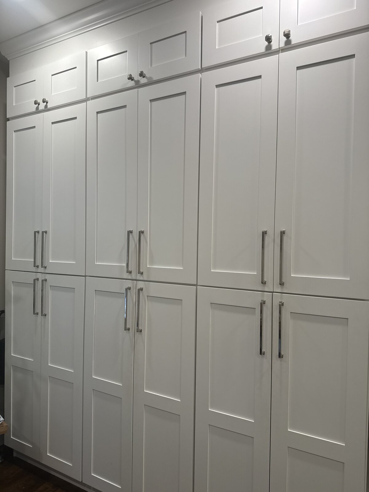 Floor-to-ceiling white shaker pantry cabinetry with brushed nickel hardware