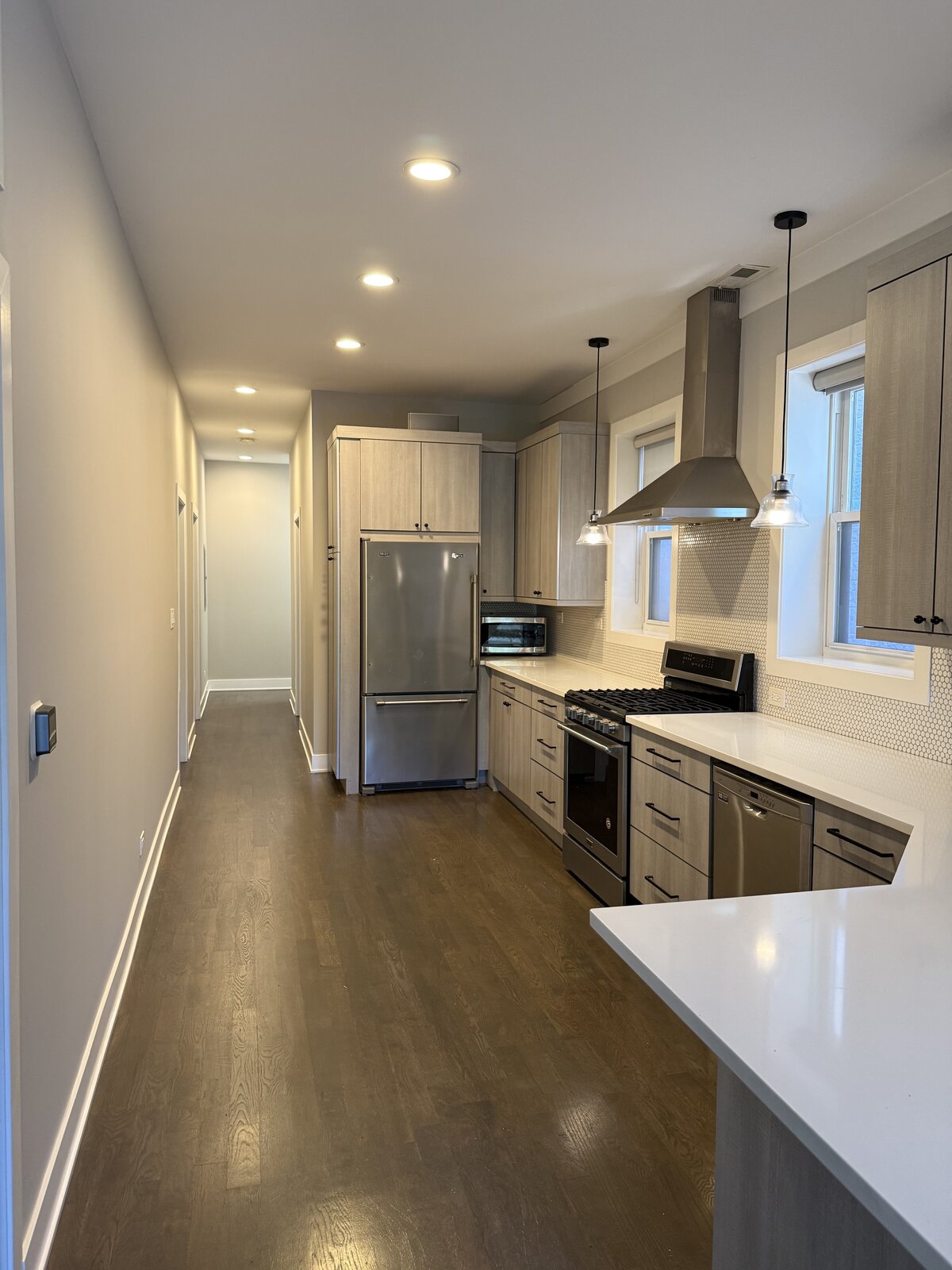 Galley kitchen with stainless appliances, penny-round tile backsplash and quartz counters